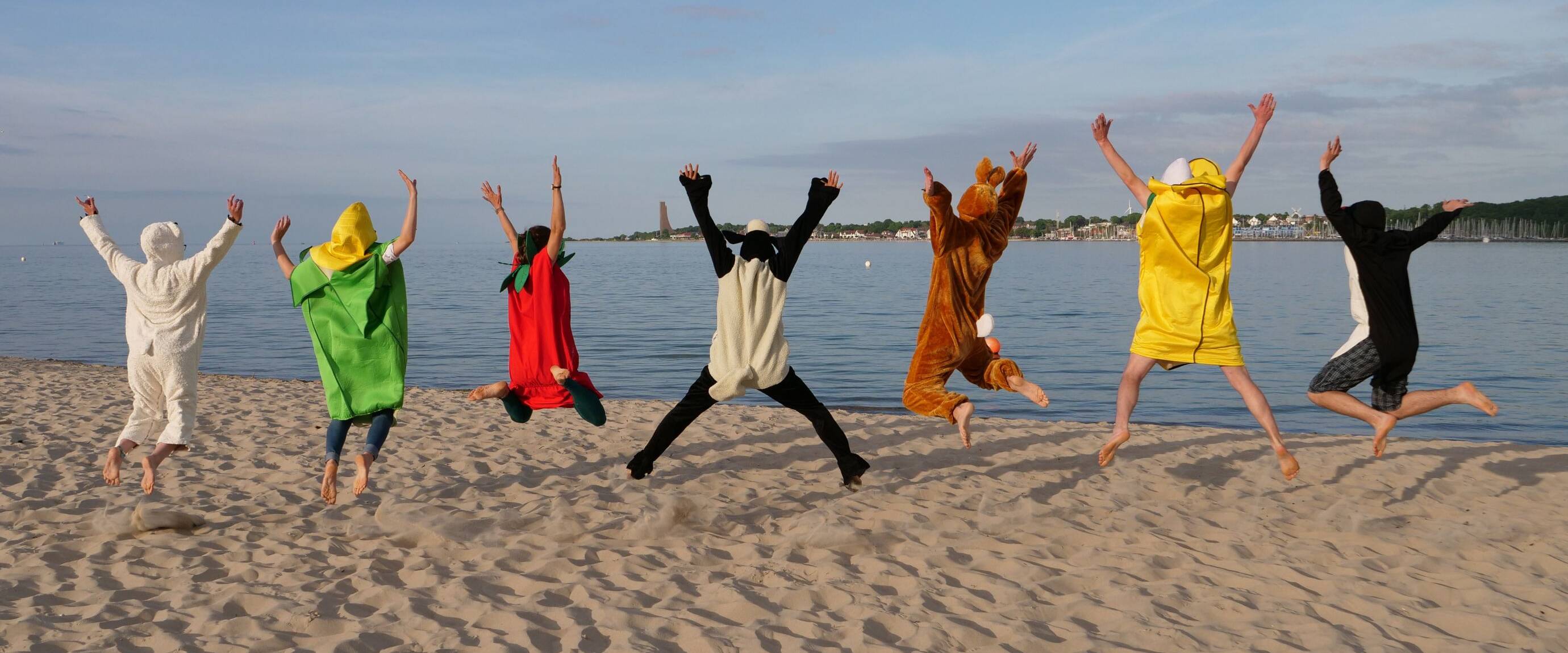 Menschen in Kostümen springen am Strand