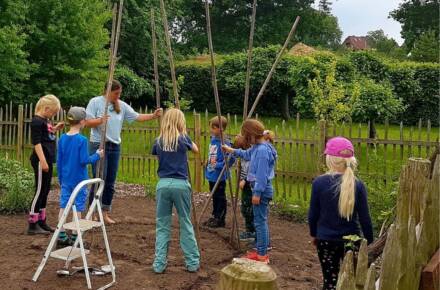 Kinder bauen ein Tipi im Garten