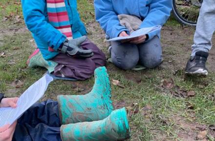 Kinder mit Gummistiefeln beim Lesen im Freien